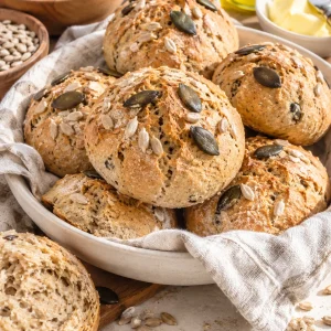 Frisch gebackene Dinkelbrötchen mit Sonnenblumenkernen und Kürbiskernen auf hellem Untergrund